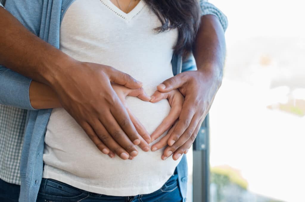 Pregnant Woman And Her African Husband Holding Hand In Heart